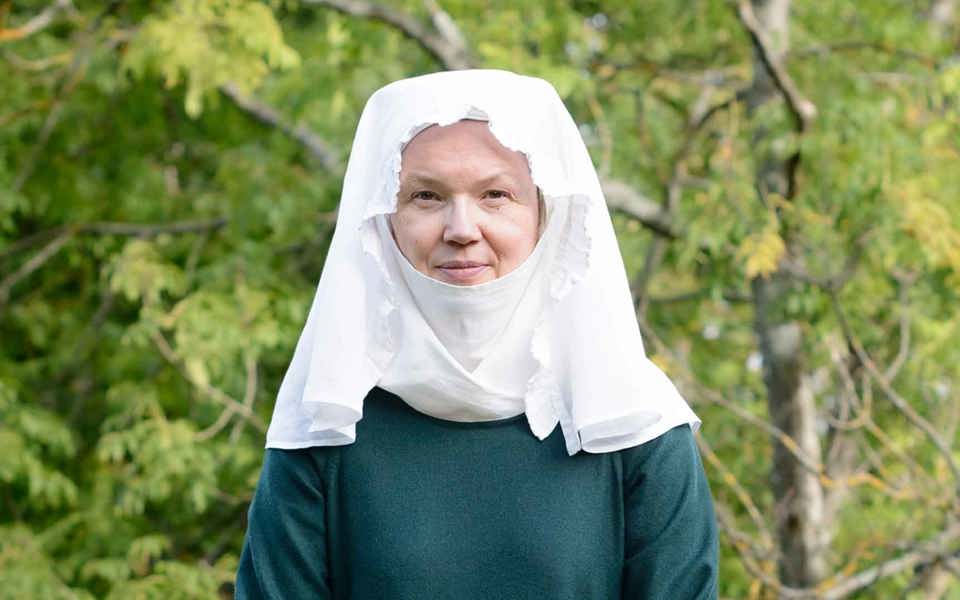 En kvinna klädd i vit huvudduk och mörkgrön helkroppsdräkt.