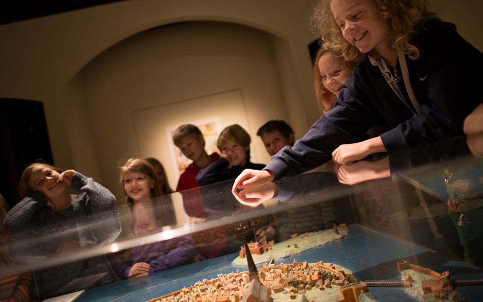 En grupp barn tittar på en modell över medeltida Stockholm.