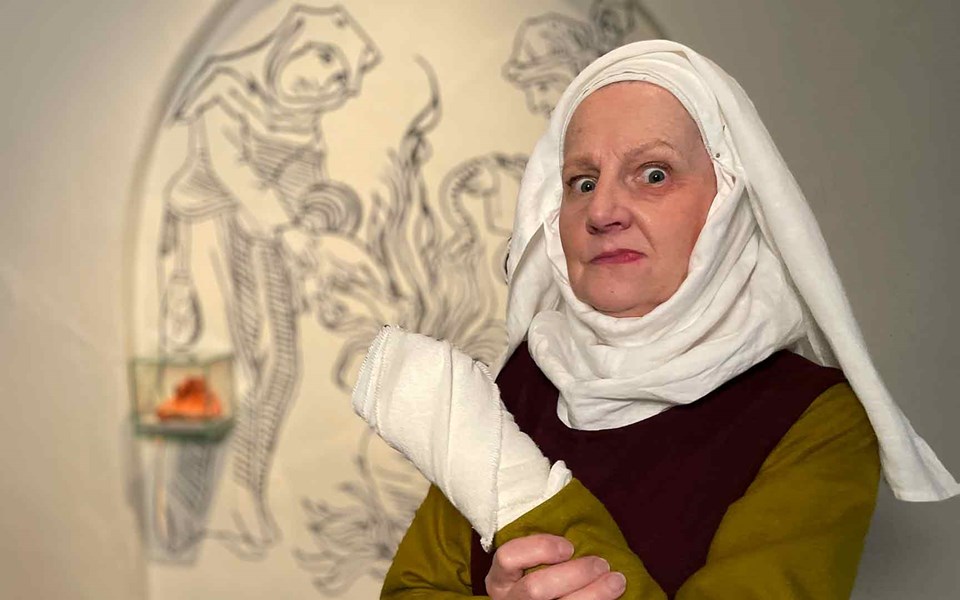 Kvinna i medeltida kläder med svullen läpp, blåtira och bandage runt ena handen.